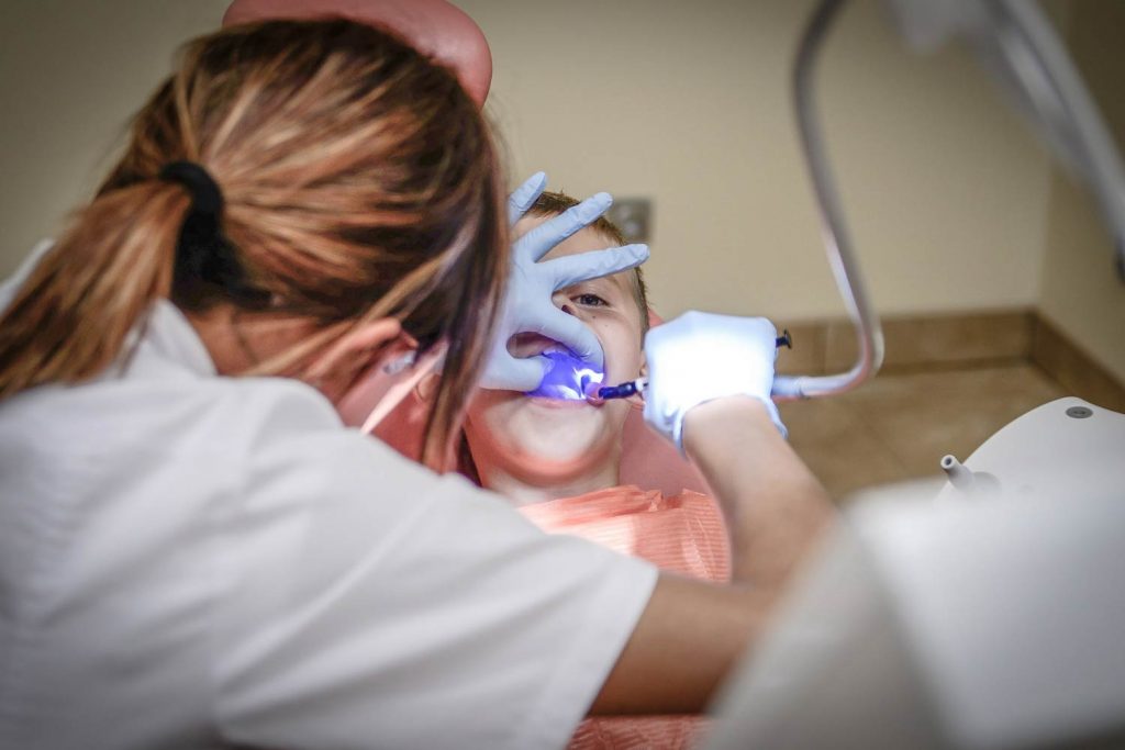 Dentista realizando un tratamiento dental a un paciente en una clínica moderna, destacando la profesionalidad y el cuidado en Granada centro.