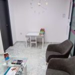 Sala de espera con sillas cómodas, mesa de cristal y área infantil, mostrando un ambiente relajado y familiar en una clínica dental de Granada centro.