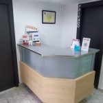 Mostrador de recepción con diseño moderno y certificado en la pared, representando la profesionalidad y organización de un dentista en Granada centro.