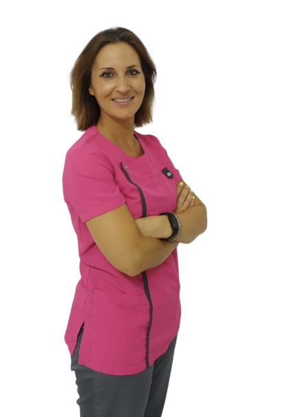Dentista con uniforme rosa y brazos cruzados, destacando la confianza y experiencia en los tratamientos dentales realizados en Granada centro.