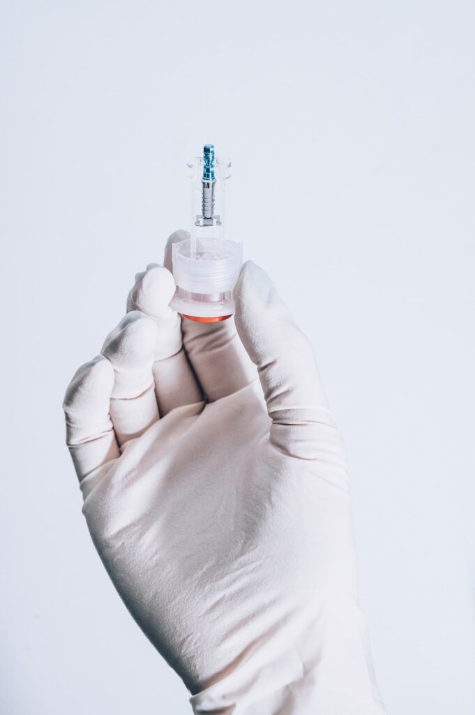Primer plano de una mano con guantes sosteniendo un implante dental, destacando los beneficios de los implantes dentales para la salud bucal y la estética.