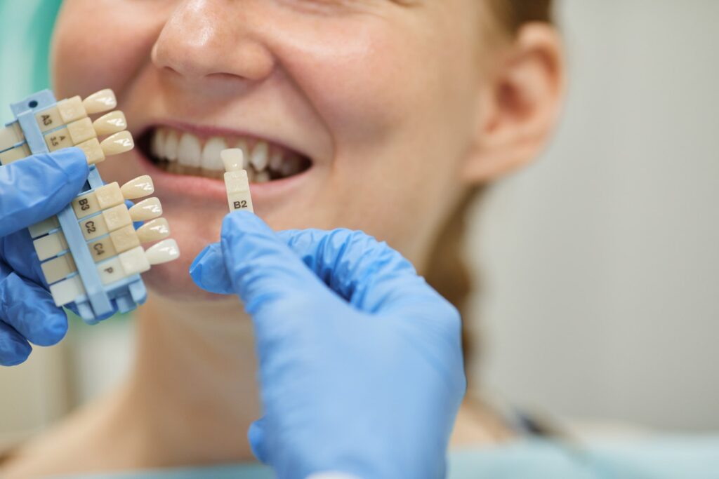 Dentista seleccionando el tono adecuado para un implante dental, asegurando la compatibilidad estética y calidad en el proceso de implantación.