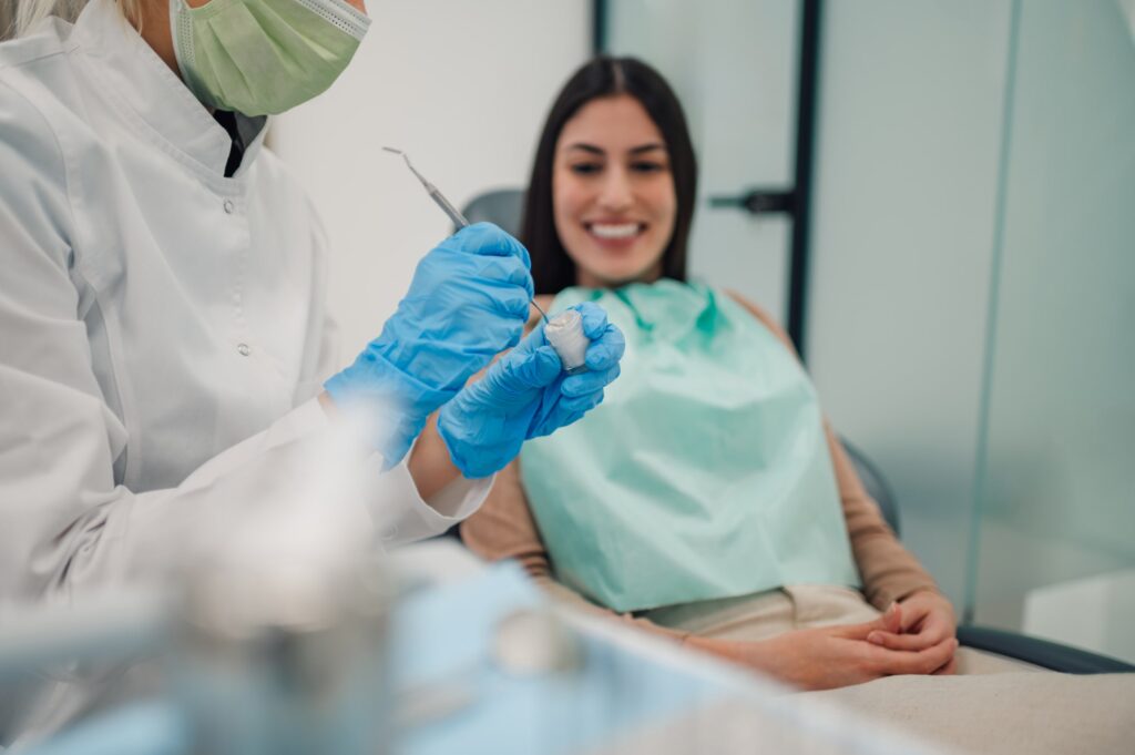 Dentista mostrando un implante dental a una paciente durante una consulta en una clínica, destacando prácticas relacionadas con el control de la inflamación.