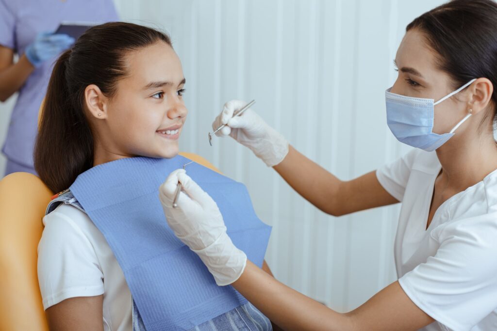 Imagen de una dentista examinando los dientes de una paciente en una clínica dental. Representa la importancia de los empastes en la salud bucodental para tratar caries y prevenir problemas mayores.