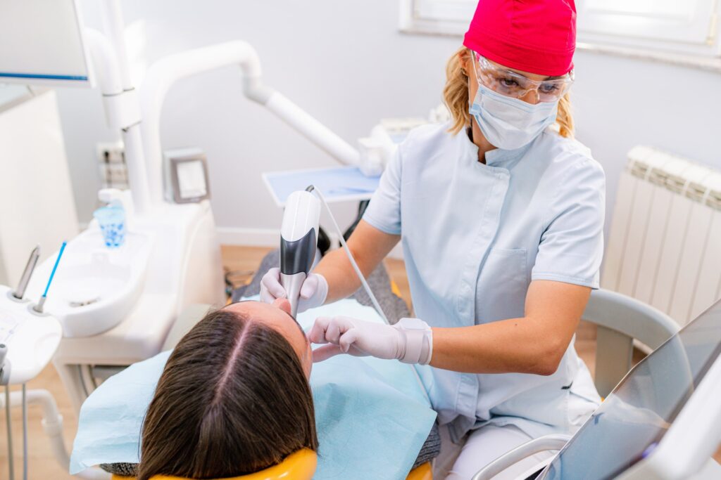Dentista realizando una revisión a paciente después de un recontorneado dental, enfocándose en los cuidados postoperatorios necesarios para una óptima recuperación.
