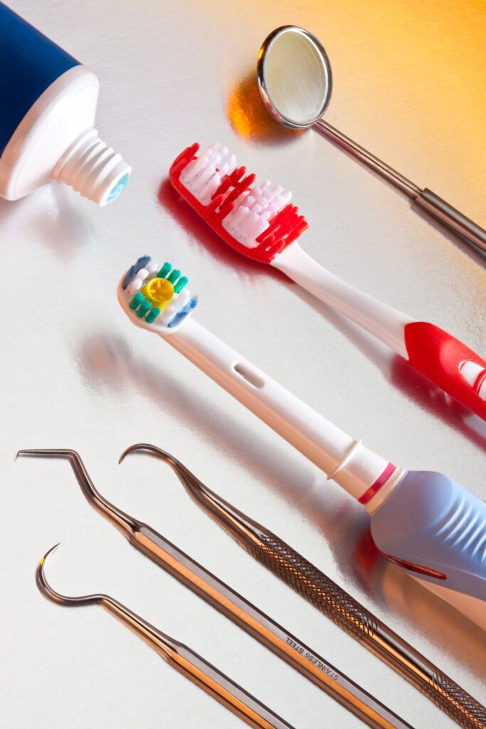 Cepillos de dientes, pasta dental y herramientas odontológicas sobre una superficie brillante, representando los elementos clave para mantener una higiene dental adecuada.