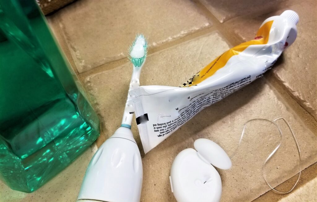 Fotografía de herramientas y tecnologías para cuidados postoperatorios dentales, incluyendo un cepillo de dientes eléctrico, pasta dental, hilo dental y enjuague bucal, elementos esenciales para mantener la higiene oral tras una cirugía y prevenir infecciones o complicaciones.