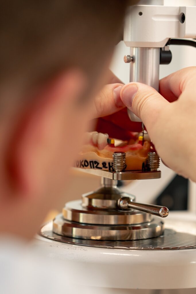 Primer plano de un técnico dental trabajando en un modelo dental con herramientas especializadas en un laboratorio, representando el análisis y fabricación para determinar la duración estimada de las carillas dentales.