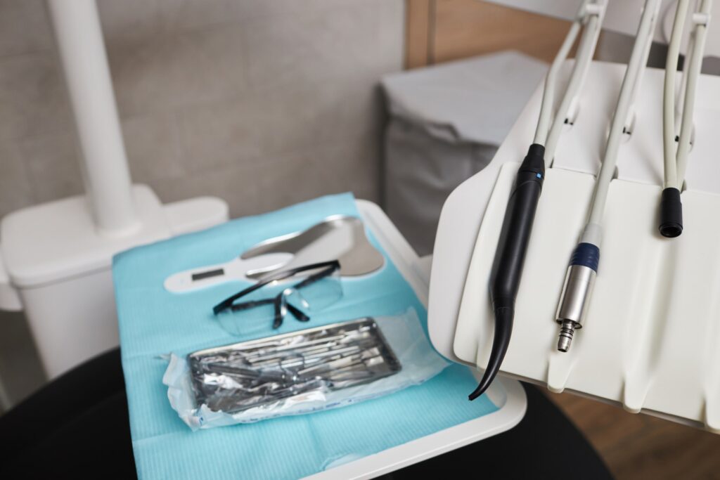 Instrumental odontológico esterilizado y listo para ser utilizado en el proceso de recontorneado dental, mostrando una bandeja con herramientas, gafas de protección y equipos dentales sobre una mesa en la clínica.