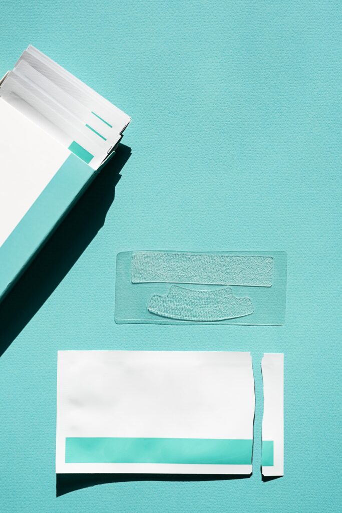 Empaque y tiras blanqueadoras dentales sobre una superficie azul, representando un método popular de blanqueamiento dental casero. Imagen ilustrativa para responder a la pregunta: ¿Cuánto dura un blanqueamiento dental?