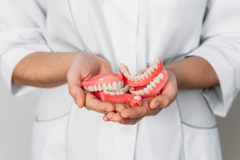 Imagen de un profesional de la salud sosteniendo varias prótesis dentales, ilustrando el concepto de ortopedia funcional y su aplicación en el tratamiento de problemas dentales y de la mordida.