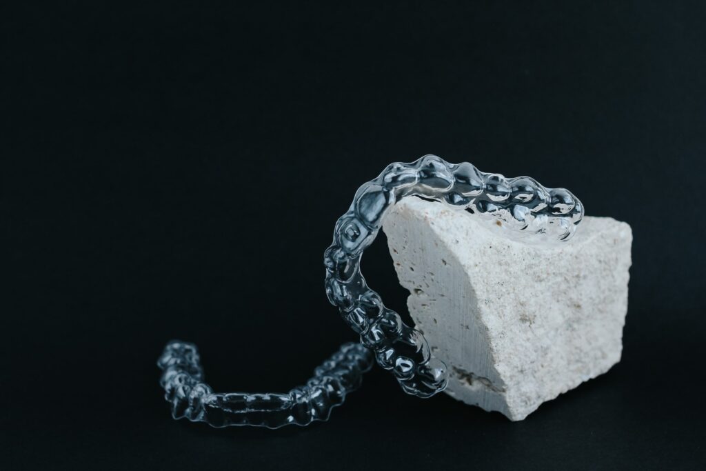 Alineador dental transparente sobre una piedra blanca, utilizado en ortopedia funcional en adultos para corregir la posición dental de manera estética y eficiente.