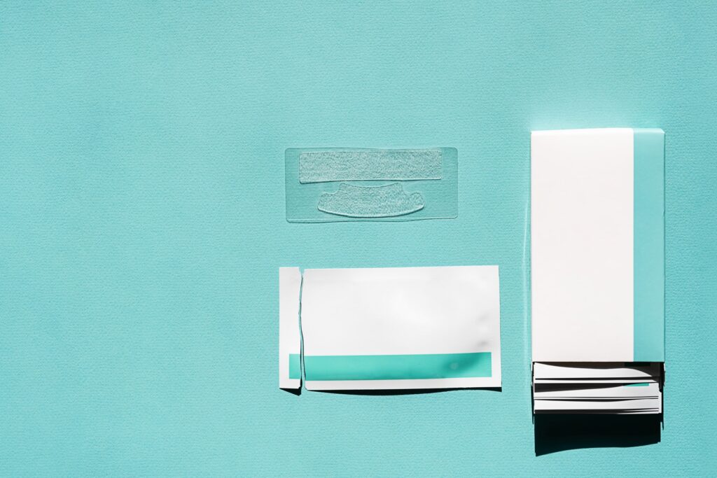 Kit de tiras blanqueadoras dentales sobre fondo azul, mostrando el empaque y las tiras listas para usar, ideal para destacar los beneficios del blanqueamiento dental en casa.