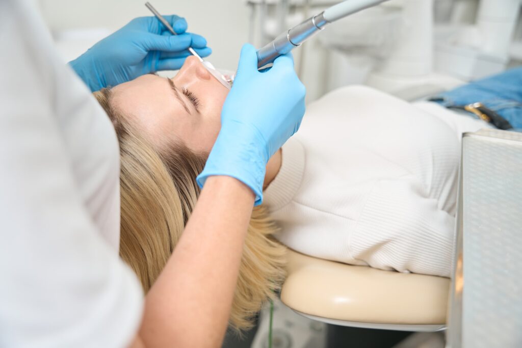 Paciente recibiendo un tratamiento profesional en una clínica dental, ilustrando las contraindicaciones del blanqueamiento dental y la importancia de la evaluación previa por un especialista.