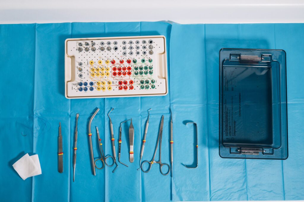 Bandeja con instrumental odontológico y kit de cirugía sobre mesa azul, representando los factores que influyen en el precio del recontorneado dental en Granada, como el tipo de herramientas, la tecnología utilizada y la calidad del material empleado en la clínica dental.