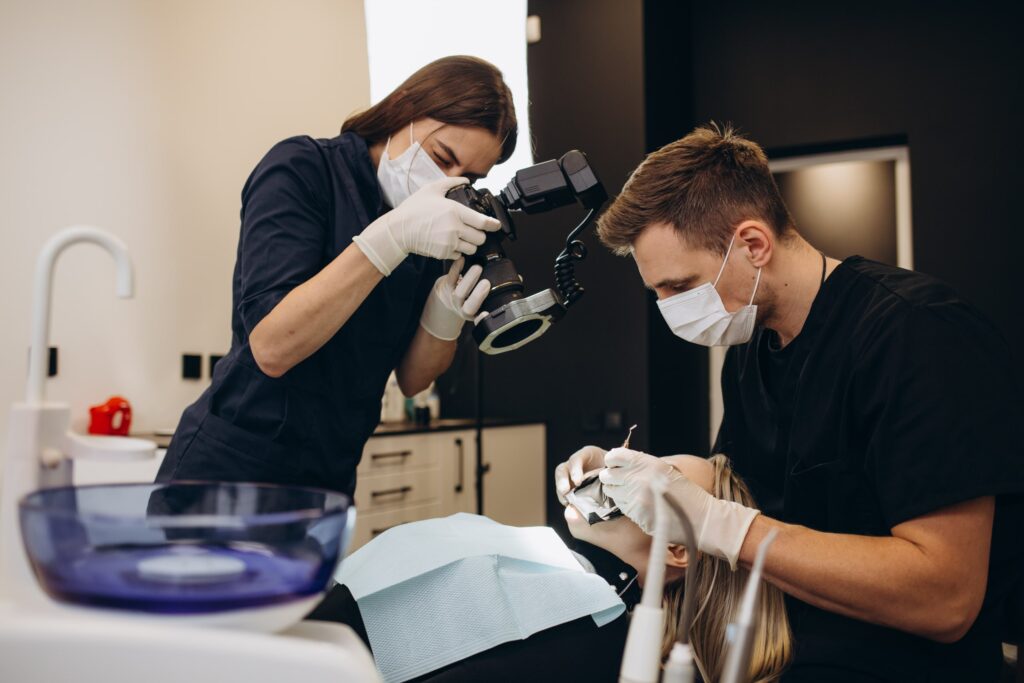 Profesionales odontológicos realizando un tratamiento de blanqueamiento dental a un paciente en una clínica, ilustrando los riesgos del abuso en el blanqueamiento dental.
