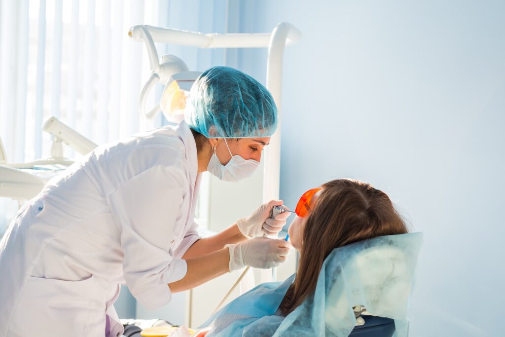 Imagen de una joven recibiendo tratamiento dental profesional en una clínica, ilustrando los factores económicos y la accesibilidad del tratamiento odontológico para mejorar la salud bucal y destacar la importancia de opciones asequibles y de calidad.