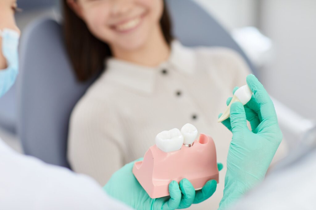 Dentista explicando a una paciente los cuidados y recomendaciones para la dieta después de una extracción dental, usando un modelo de dientes para ilustrar el procedimiento.