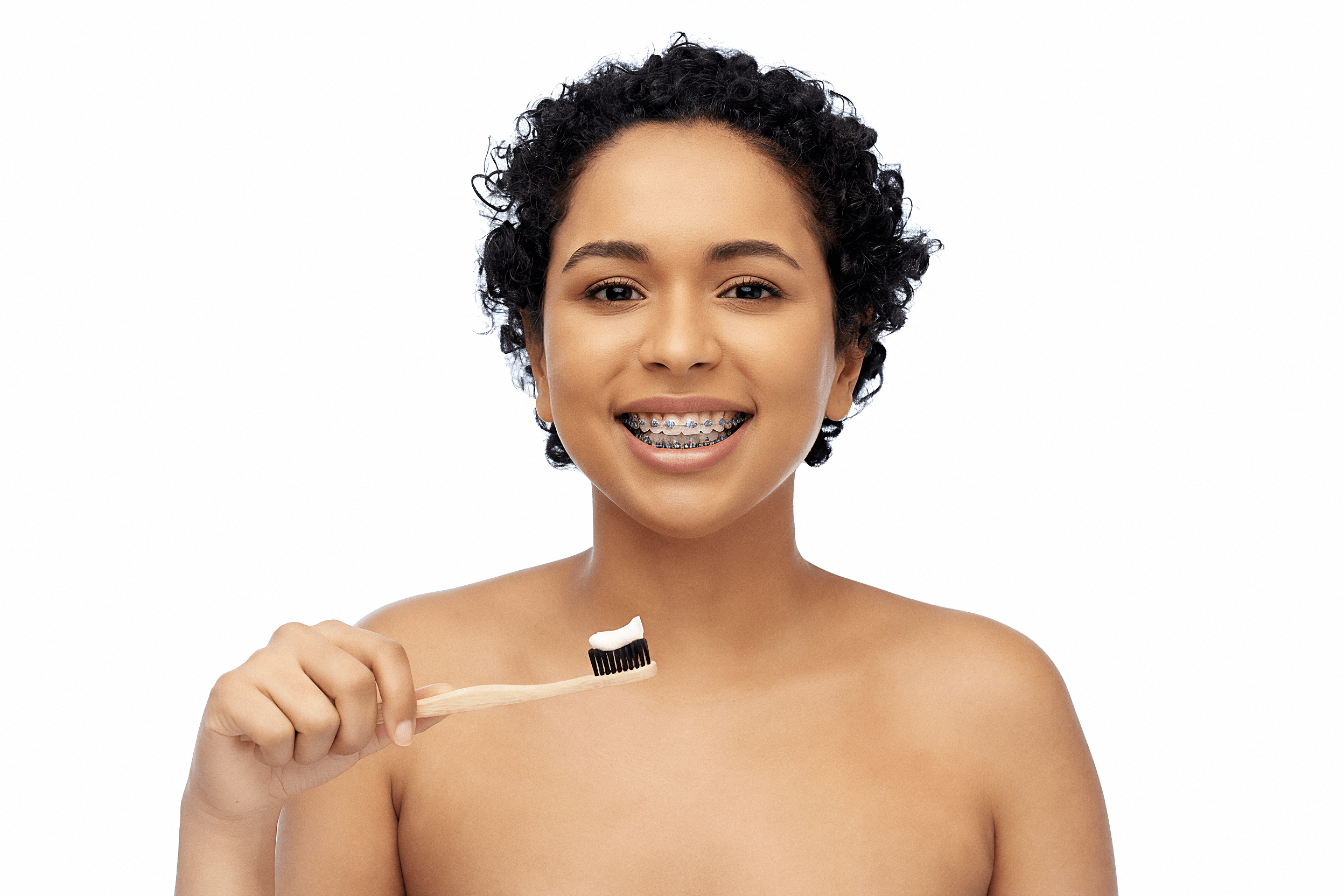 Persona joven sosteniendo un cepillo de dientes con pasta dental, mostrando la rutina de higiene y cuidados durante el tratamiento con brackets metálicos, fundamental para evitar caries, mantener la salud bucal y lograr resultados efectivos en la ortodoncia.