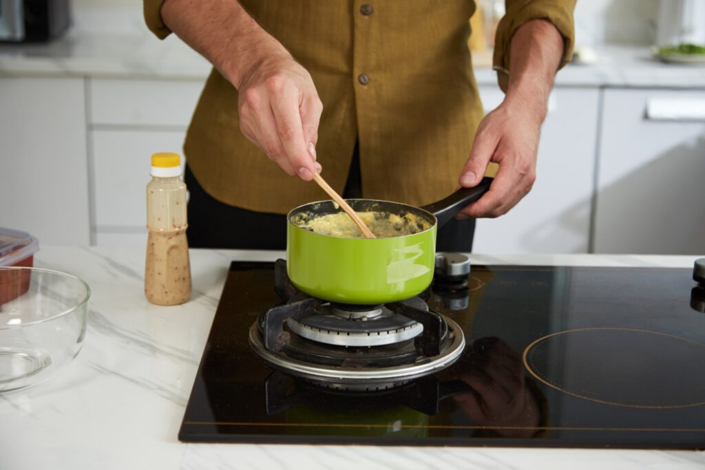 Persona cocinando puré de papas en una olla, ejemplificando la incorporación de alimentos semiblandos en la primera semana después de la intervención, parte esencial para facilitar la recuperación y mantener una dieta adecuada.