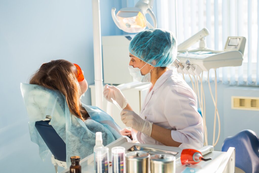 Dentista coloca una corona dental a una paciente durante el proceso de restauración dental en el consultorio, mostrando el cuidado y la precisión necesarios para el procedimiento de colocación de una corona dental.